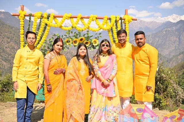 Family in yellow at a marigold haldi arch with snow peaks behind